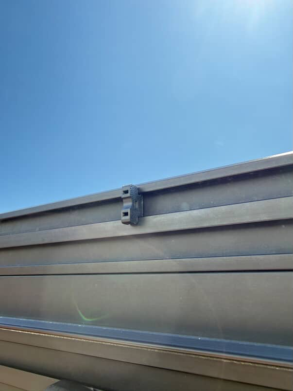 A 3D printed ziptie mount attached to a metal roof rack, used for organizing wiring.