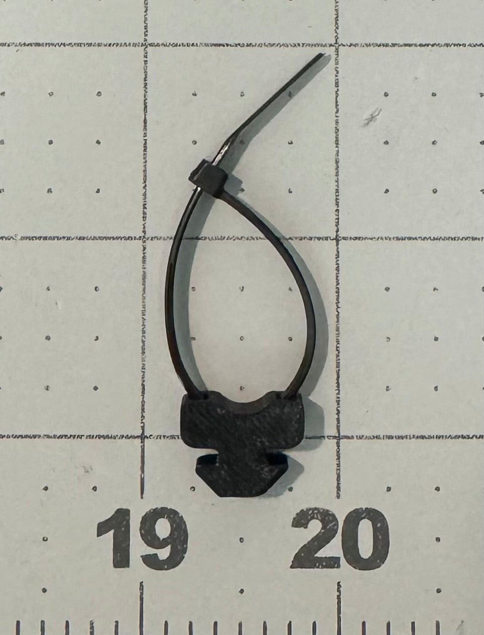 A 3D printed ziptie mount attached to a metal roof rack, used for organizing wiring.