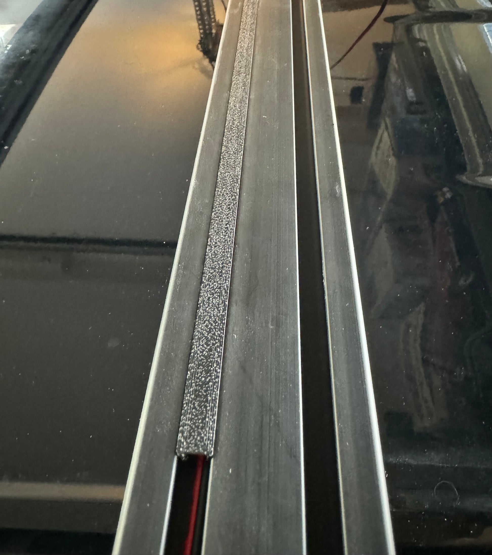 A set of black plastic wire hiders installed on a vehicle roof rack, designed to manage and route wiring along the cross bars.