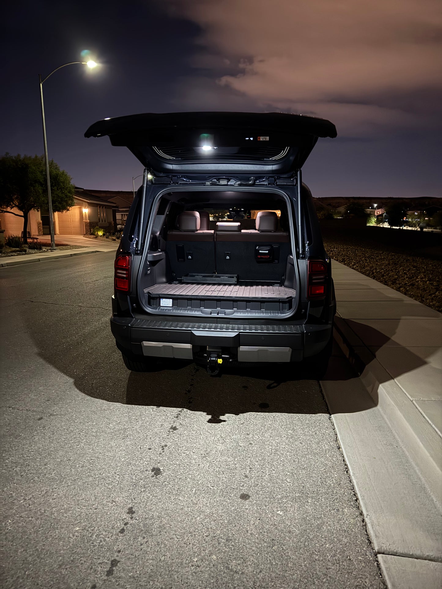 A switchable LED hatch light for Land Cruiser LC250/GX550 placed on a textured surface with the text 'LAND CRUISER' visible.
