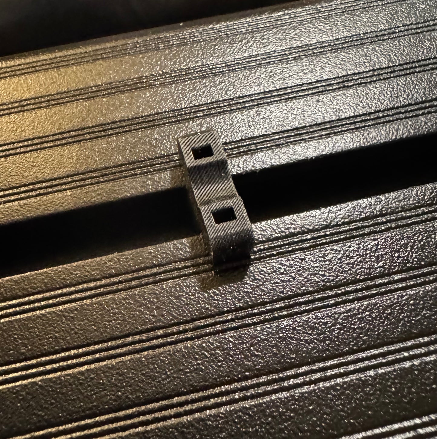 A 3D printed ziptie mount attached to a metal roof rack, used for organizing wiring.