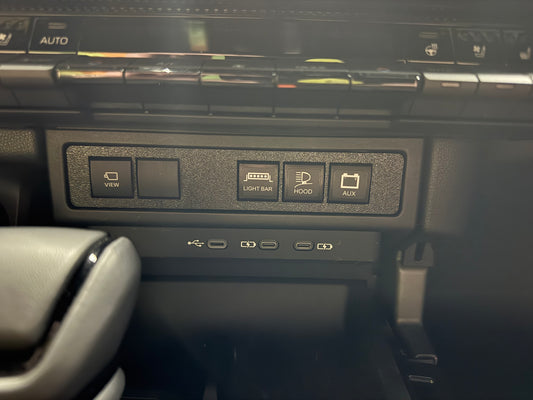 An auxiliary switch panel installed in a vehicle's dashboard, featuring several switches, set against a dark interior background.