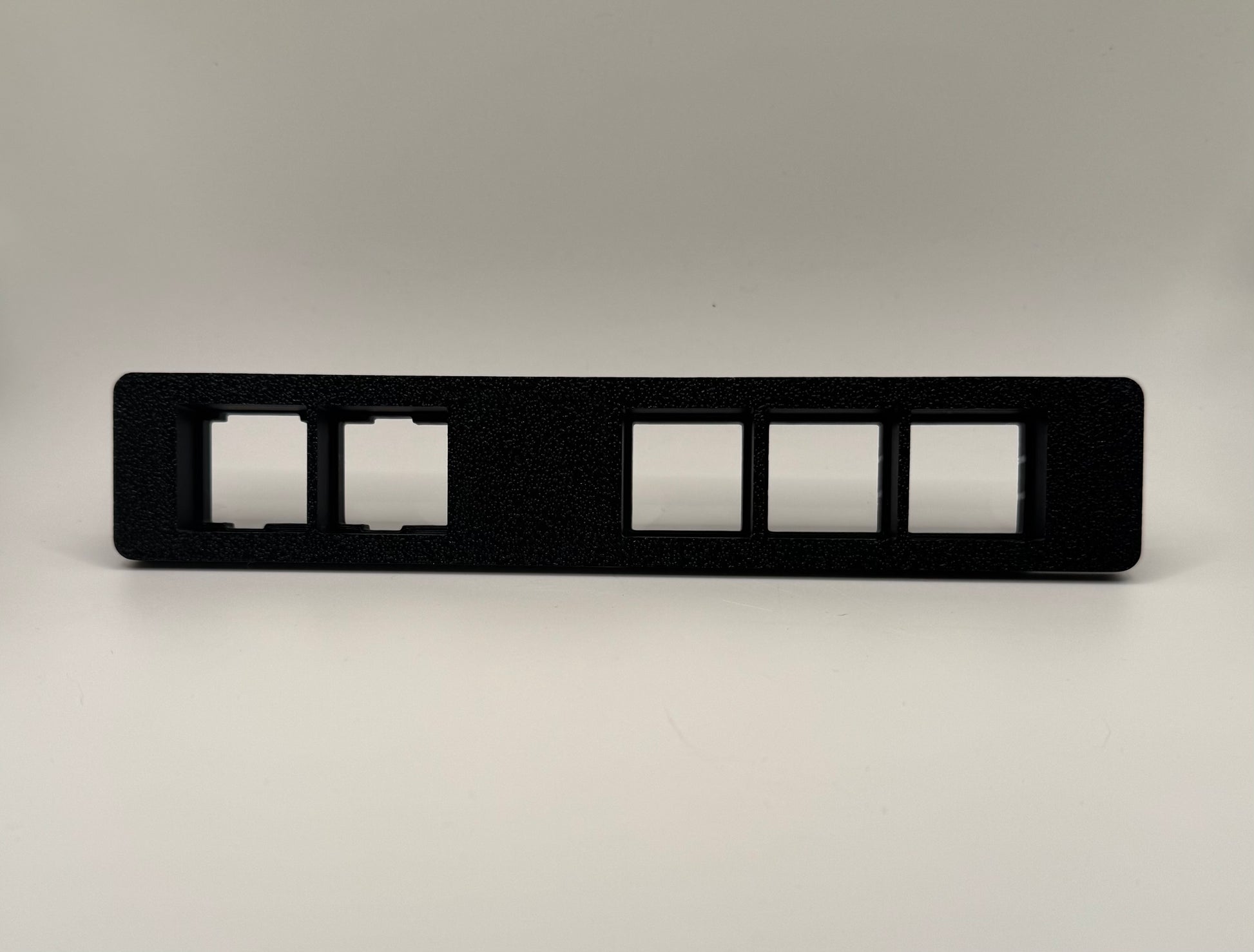 Black auxiliary switch panel designed for use in '24+up Toyota Land Cruiser, featuring multiple rectangular cutouts for switches.