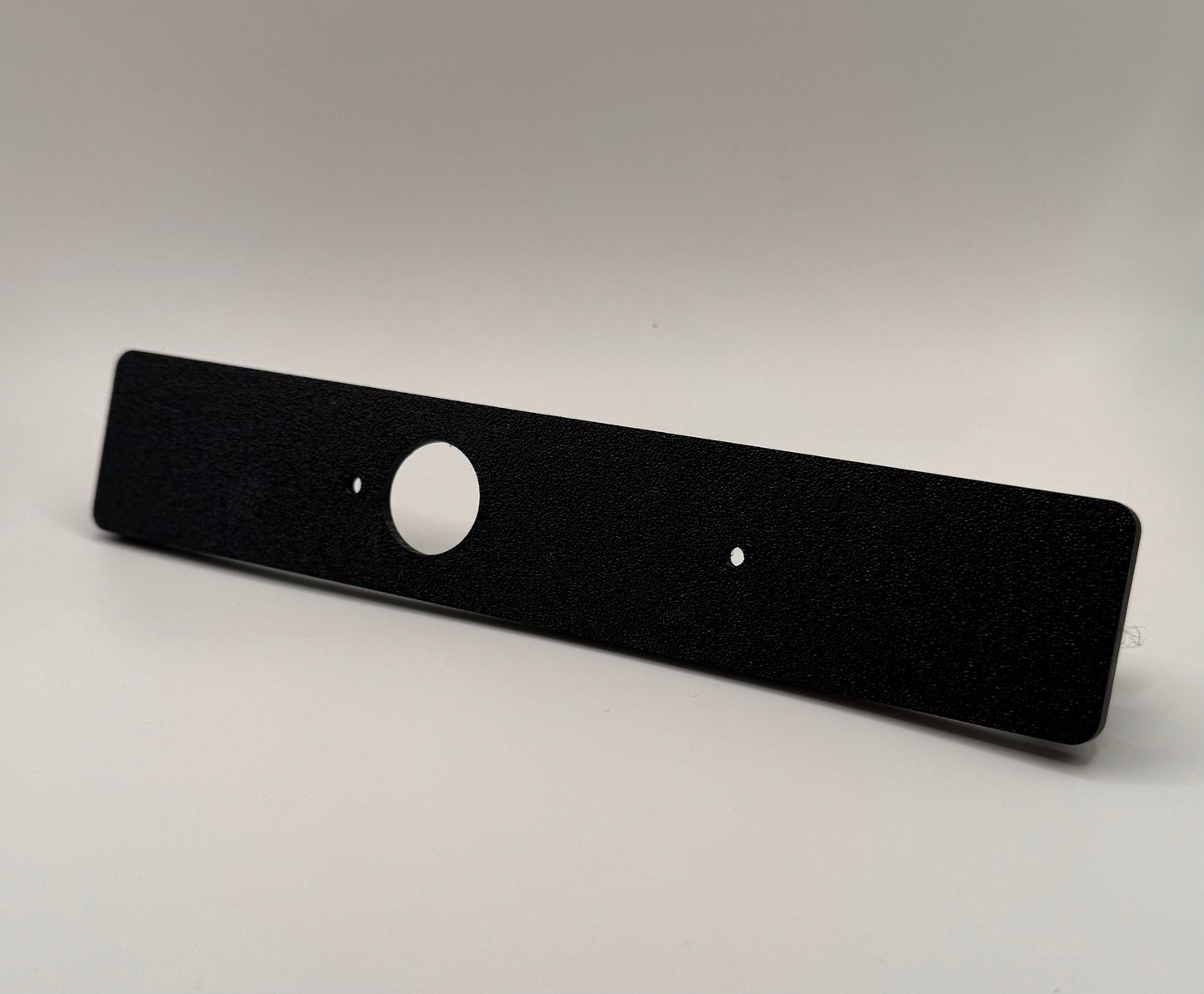 Black flat switch panel mount for LC250/Prado designed for Auxbeam, with a circular cutout in the center against a white background.