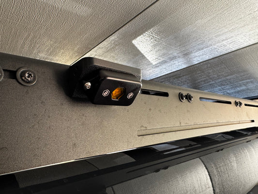 Close-up of a vehicle roof rack with a mounting bracket and electrical connector.