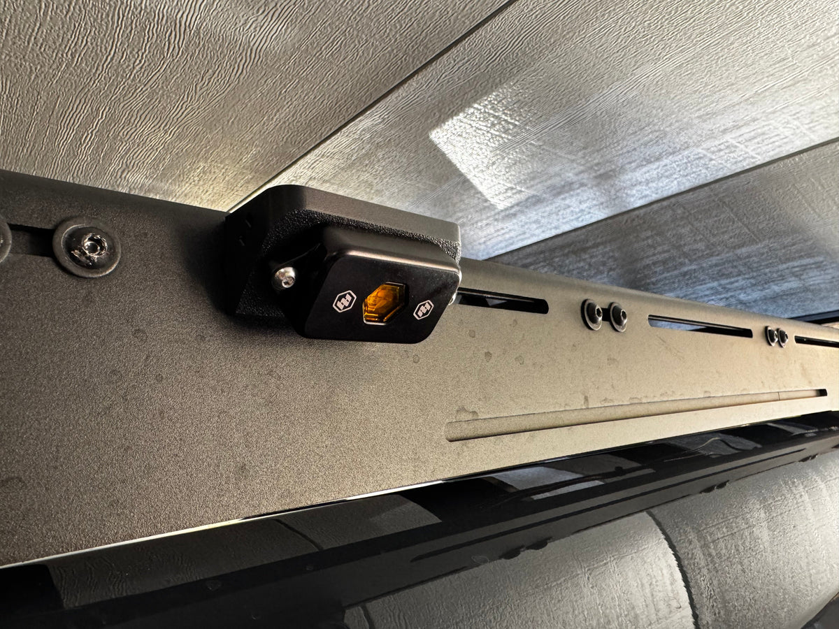 Close-up of a vehicle roof rack with a mounting bracket and electrical connector.