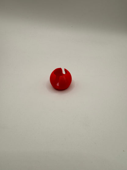 A small red plastic wall hook with a notch on the left side, mounted on a plain off-white wall.