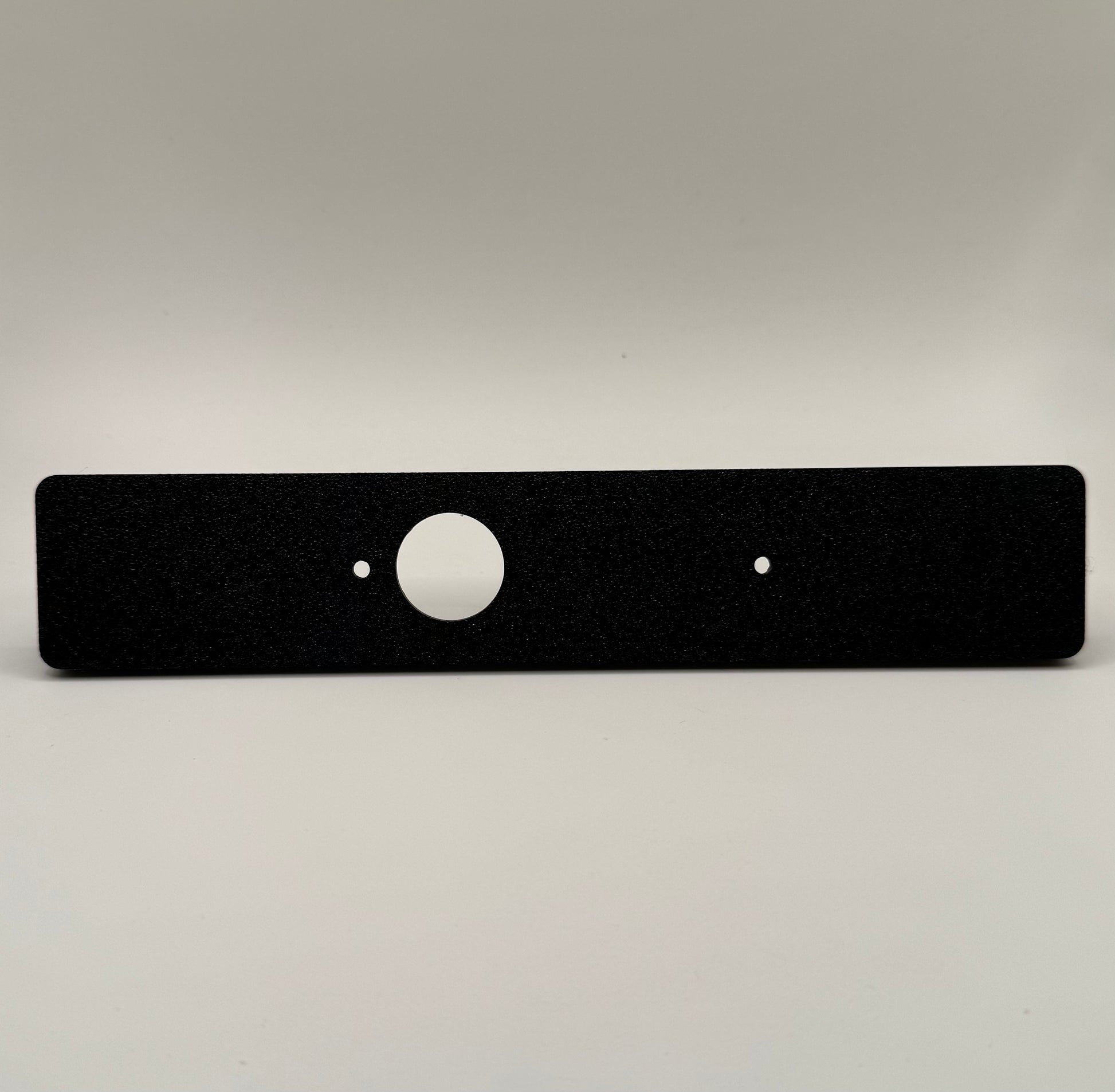 Black flat switch panel mount for LC250/Prado designed for Auxbeam, with a circular cutout in the center  against a white background.