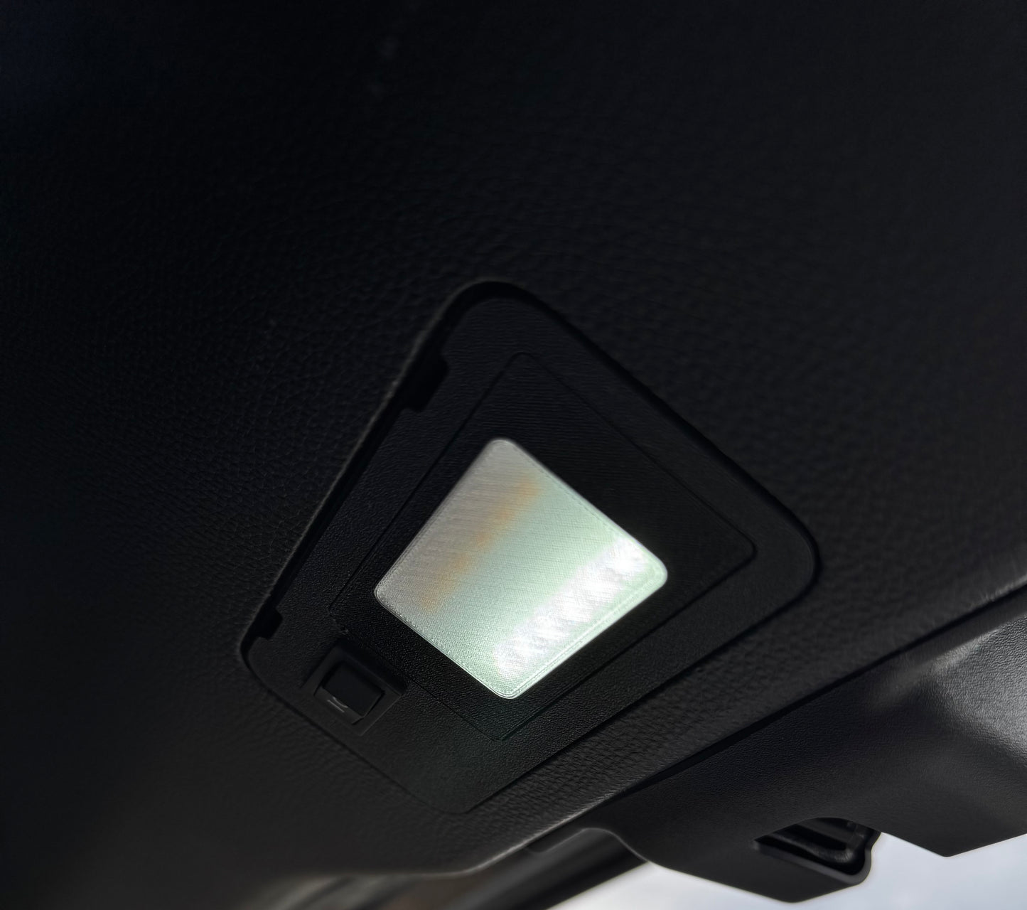 A switchable LED hatch light for Land Cruiser LC250/GX550 placed on a textured surface with the text 'LAND CRUISER' visible.