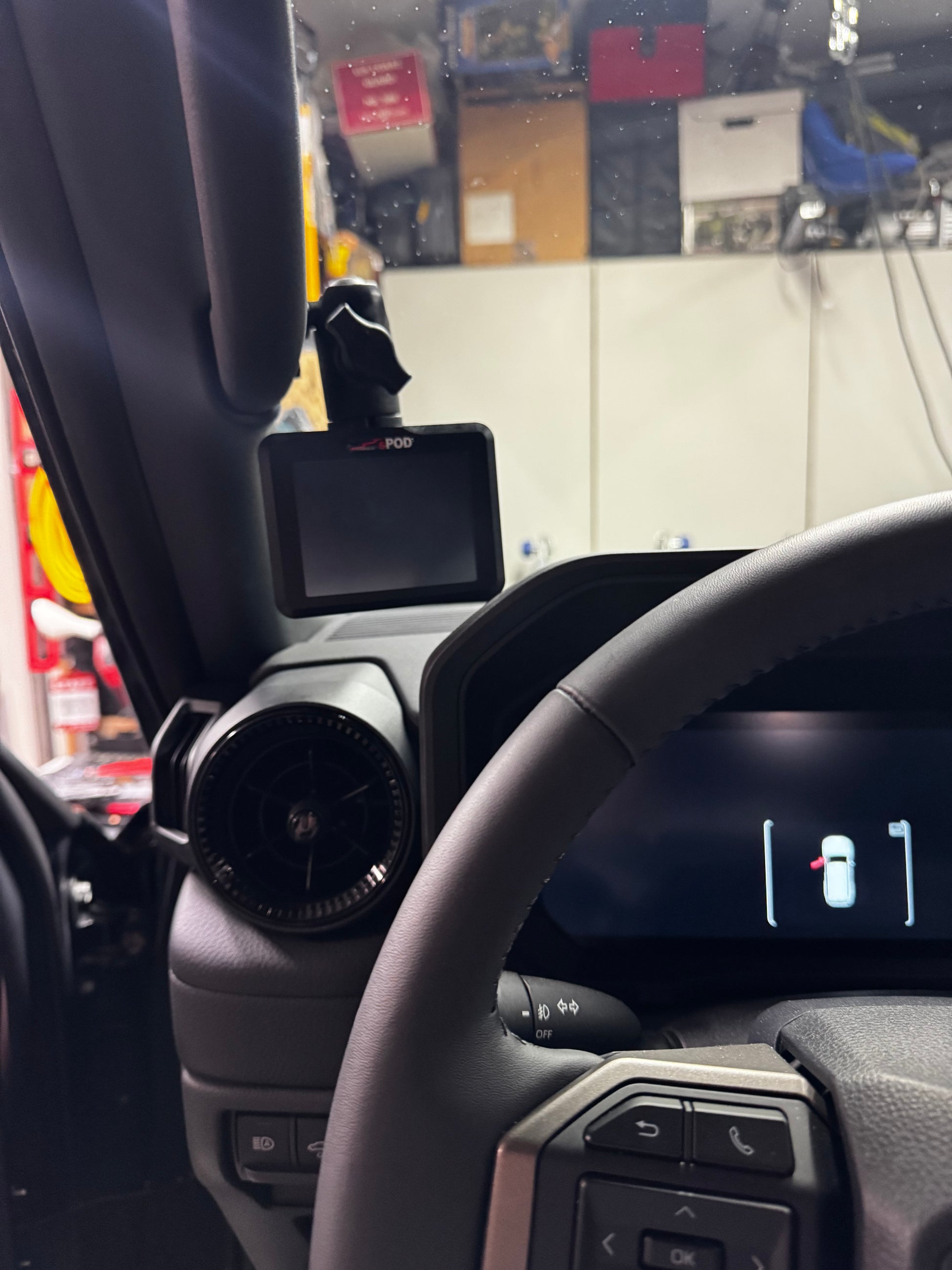 Steering wheel and dashboard of a vehicle with a mounted phone holder.