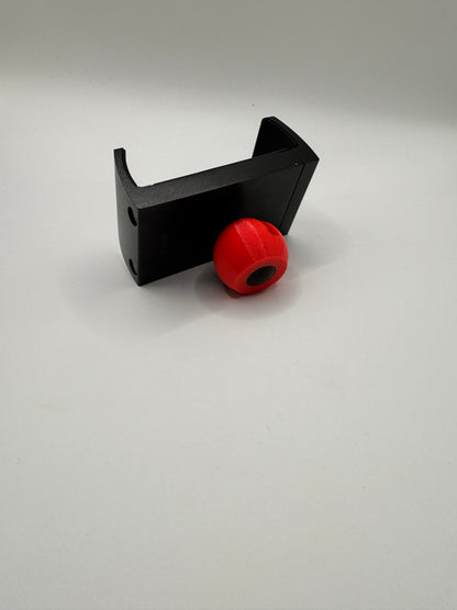 A black plastic mounting bracket with a red spherical knob or cap, photographed against a plain light gray background.