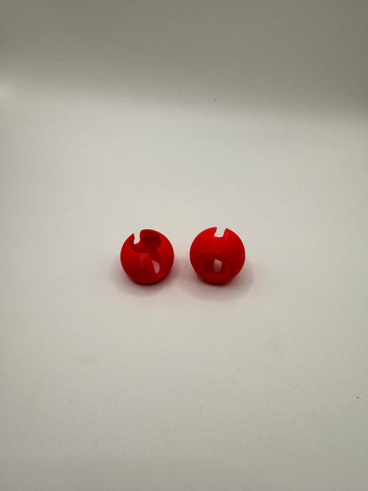 Two small glossy red plastic snap hooks or wall pegs displayed vertically on a plain off-white background.