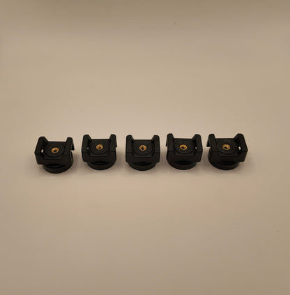 Five black plastic components with gold screws on a beige background